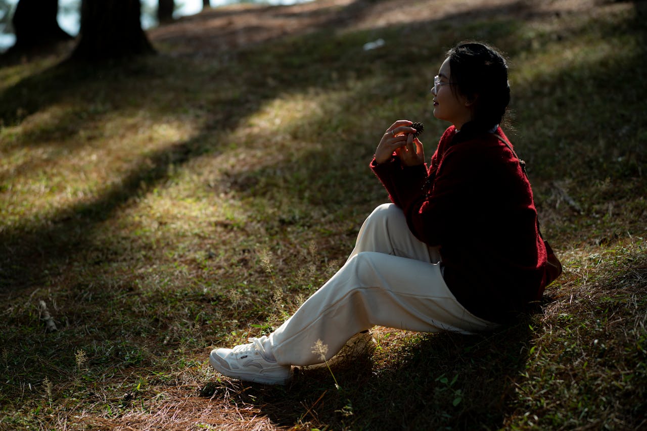 Woman relaxing in a sunlit forest in Hà Giang, Vietnam, embracing tranquility.
